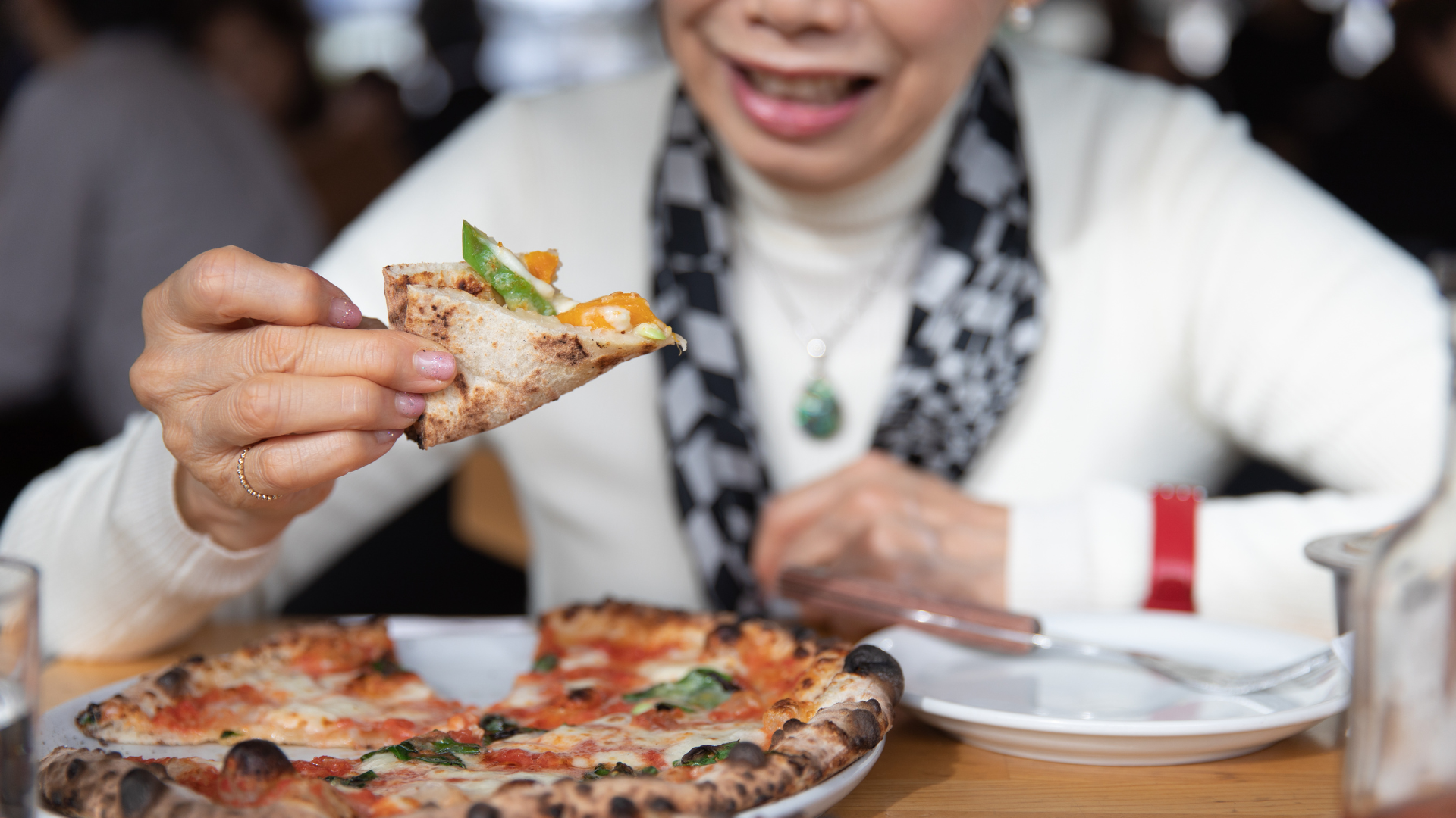Äldre kvinna äter pizza.